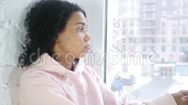 伤心难过的年轻美国黑人妇女，坐在窗前